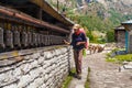 Young Woman Wearing Backpack Trekking Touching Tibetan prayer Wheels or Prayers Rolls Faithful Buddhists.Caravan Animal Royalty Free Stock Photo