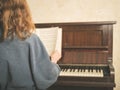 Woman at piano turning music paper