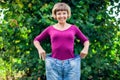 Young woman wearing big loose jeans with apple in hand - weight Royalty Free Stock Photo