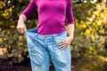 Young woman wearing big loose jeans with apple in hand - weight Royalty Free Stock Photo