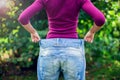 Young woman wearing big loose jeans with apple in hand - weight Royalty Free Stock Photo