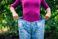 Young woman wearing big loose jeans with apple in hand - weight Royalty Free Stock Photo