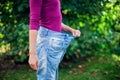 Young woman wearing big loose jeans with apple in hand - weight Royalty Free Stock Photo