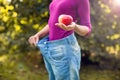Young woman wearing big loose jeans with apple in hand - weight Royalty Free Stock Photo