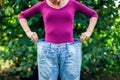 Young woman wearing big loose jeans with apple in hand - weight