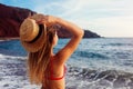 Young woman in bikini and hat relaxing on Red beach in Santorini, Greece. Girl enjoying sea and mountain landscape Royalty Free Stock Photo