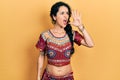 Young woman wearing bindi and bollywood clothing shouting and screaming loud to side with hand on mouth