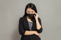 Young woman wearing a black mask holding her right cheek while lowering her head Royalty Free Stock Photo