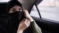 Young woman wearing black niqab. Folowing the rules woman wears the niqab while her road in the car, sitting on a