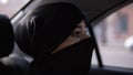 Young woman wearing black niqab. Folowing the rules woman wears the niqab while her road in the car, sitting on a