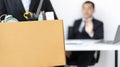 Young woman wearing a black suit raises a brown cardboard box from the office Royalty Free Stock Photo