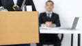 Young woman wearing a black suit raises a brown cardboard box from the office Royalty Free Stock Photo