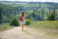 Young woman with a leather backpack on a summer rural road