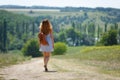 Young woman with a leather backpack on a summer rural road Royalty Free Stock Photo