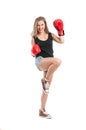 Young woman wearing boxing gloves and raising foot and hand Royalty Free Stock Photo