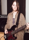 young woman wearing casual clothes and playing electric bass guitar looking aside. female bass guitarist standing in a Royalty Free Stock Photo