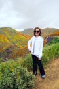 Young woman wearing casual white jean jacket and yoga pants poses on the trail at Walker Canyon during the California Poppy super Royalty Free Stock Photo