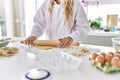 Young woman wearing cook uniform kneading pasta dough at kitchen