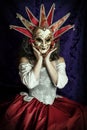 A young woman wearing a corset, a Venetian carnival mask and red skirt and sitting in an opulent, vintage setting Royalty Free Stock Photo