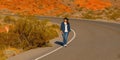 Young woman wearing a cowboy hat walking down a lonesome road in the desert of Arizona Royalty Free Stock Photo