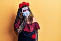 Young woman wearing day of the dead costume wearing medical mask looking stressed and nervous with hands on mouth biting nails