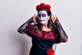 Young woman wearing day of the dead costume over white trying to hear both hands on ear gesture, curious for gossip