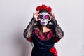 Young woman wearing day of the dead costume over white trying to open eyes with fingers, sleepy and tired for morning fatigue