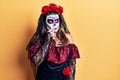 Young woman wearing day of the dead costume over yellow looking stressed and nervous with hands on mouth biting nails