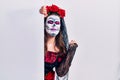 Young woman wearing day of the dead custome holding blank empty banner very happy and excited doing winner gesture with arms