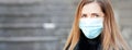 Young woman wearing disposable blue virus face mouth nose mask, closeup portrait, banner with space for text left side. Royalty Free Stock Photo