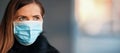 Young woman wearing disposable blue virus face mouth nose mask, closeup portrait, banner with space for text right side.