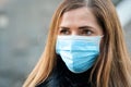 Young woman wearing disposable blue virus face mouth nose mask, closeup portrait. Coronavirus covid-19 outbreak prevention concept