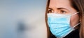 Young woman wearing disposable blue virus face mouth nose mask, closeup portrait - wide banner with space for text left side. Royalty Free Stock Photo