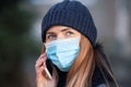 Young woman wearing disposable blue face mouth nose mask talking on mobile phone. Closeup detail, can be used during Royalty Free Stock Photo