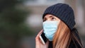 Young woman wearing disposable blue face mouth nose mask talking on mobile phone. Closeup detail, can be used during Royalty Free Stock Photo