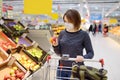 Young woman wearing disposable medical mask shopping in supermarket during coronavirus pneumonia outbreak