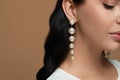Young woman wearing elegant pearl earrings on brown background, closeup. Space for text Royalty Free Stock Photo