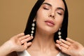 Young woman wearing elegant pearl earrings on brown background, closeup Royalty Free Stock Photo