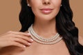 Young woman wearing elegant pearl jewelry on brown background, closeup Royalty Free Stock Photo