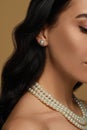 Young woman wearing elegant pearl jewelry on brown background, closeup Royalty Free Stock Photo