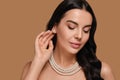 Young woman wearing elegant pearl jewelry on brown background, space for text Royalty Free Stock Photo