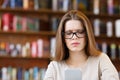 Young woman wearing eyeglasses sitting in cafe and surfing her phone Royalty Free Stock Photo