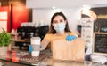 Young woman wearing face mask while serving takeaway breakfast and coffee inside cafeteria restaurant - Worker preparing healthy Royalty Free Stock Photo