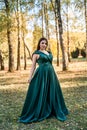 Young woman wearing fashionable green dress walking in autumn park Royalty Free Stock Photo