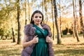 Young woman wearing fashionable green dress walking in autumn park Royalty Free Stock Photo