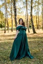 Young woman wearing fashionable green dress walking in autumn park Royalty Free Stock Photo