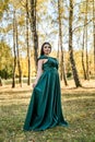 Young woman wearing fashionable green dress walking in autumn park Royalty Free Stock Photo