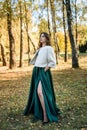 Young woman wearing fashionable green dress walking in autumn park Royalty Free Stock Photo