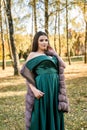 Young woman wearing fashionable green dress walking in autumn park Royalty Free Stock Photo