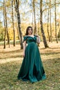 Young woman wearing fashionable green dress walking in autumn park Royalty Free Stock Photo